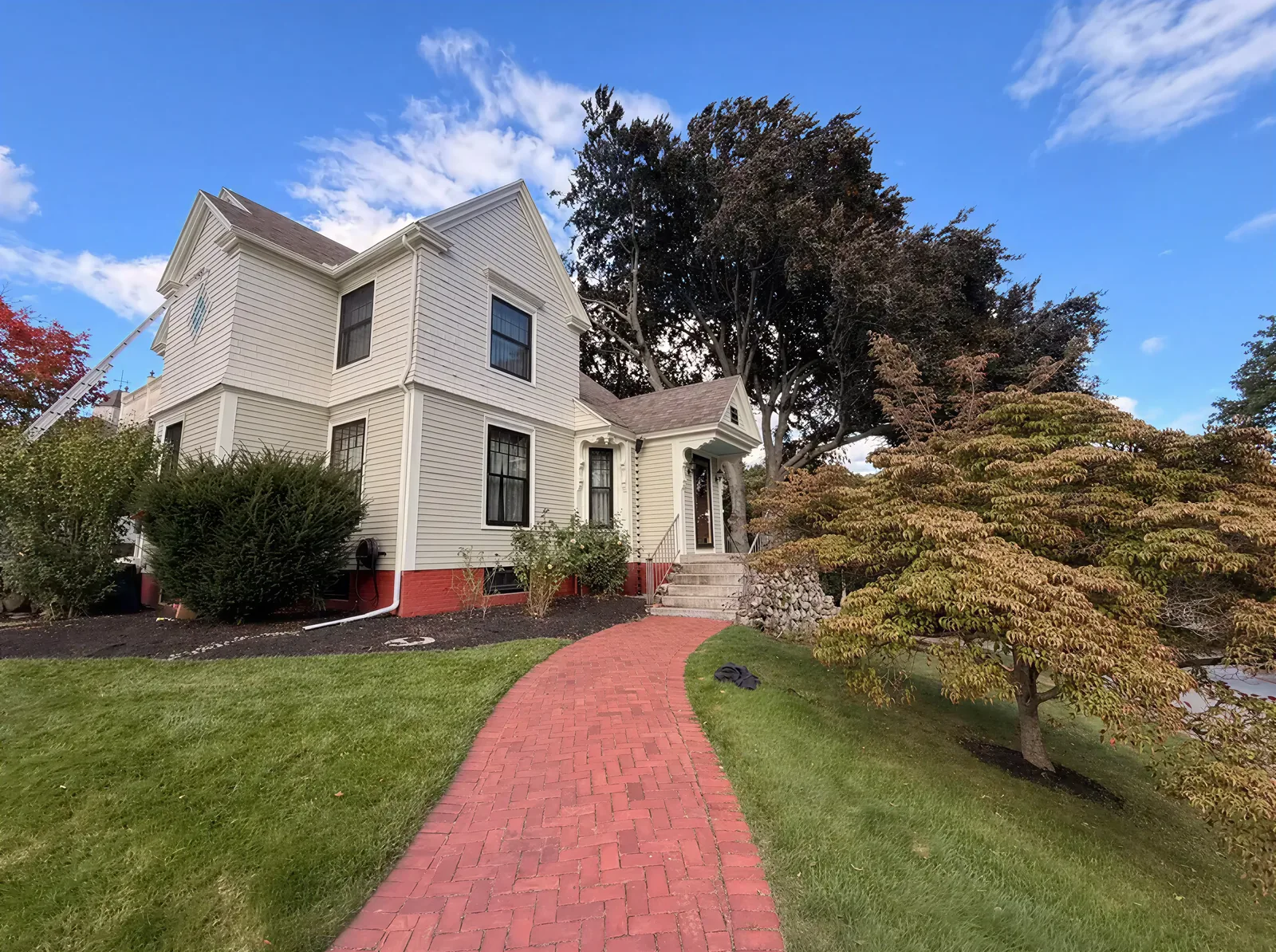 A cream Victorian house with dark trim and a red brick walk, painted by Maldonado's.